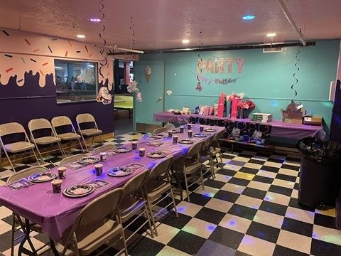 The Ice Cream Room set for a birthday party with purple tablecloths and a sprinkle-painted wall