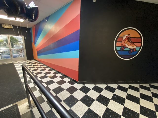 Deleta's lobby with a checkered floor, a rainbow sunburst mural and a painted roller skate