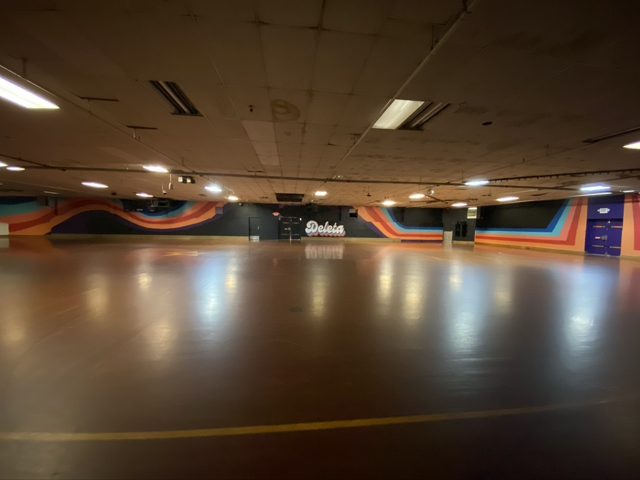The empty Deleta rink floor with rainbow stripes painted along the walls