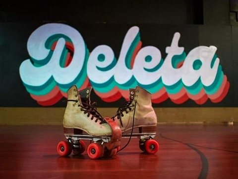 A pair of vintage roller skates on the rink floor in front of the Deleta mural